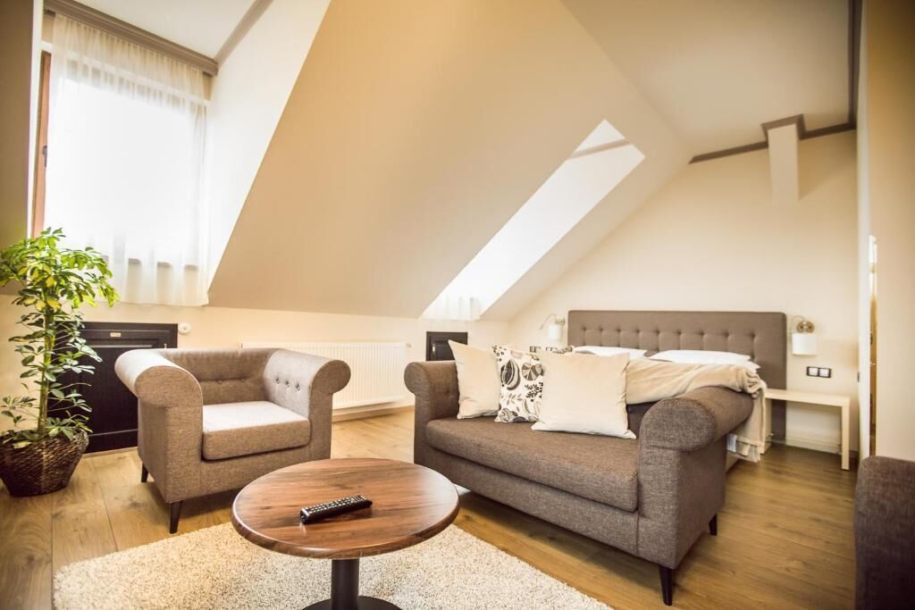A modern living room with a sofa, two armchairs, a coffee table, and a potted plant.