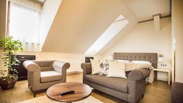 A modern living room with a sofa, two armchairs, a coffee table, and a potted plant.