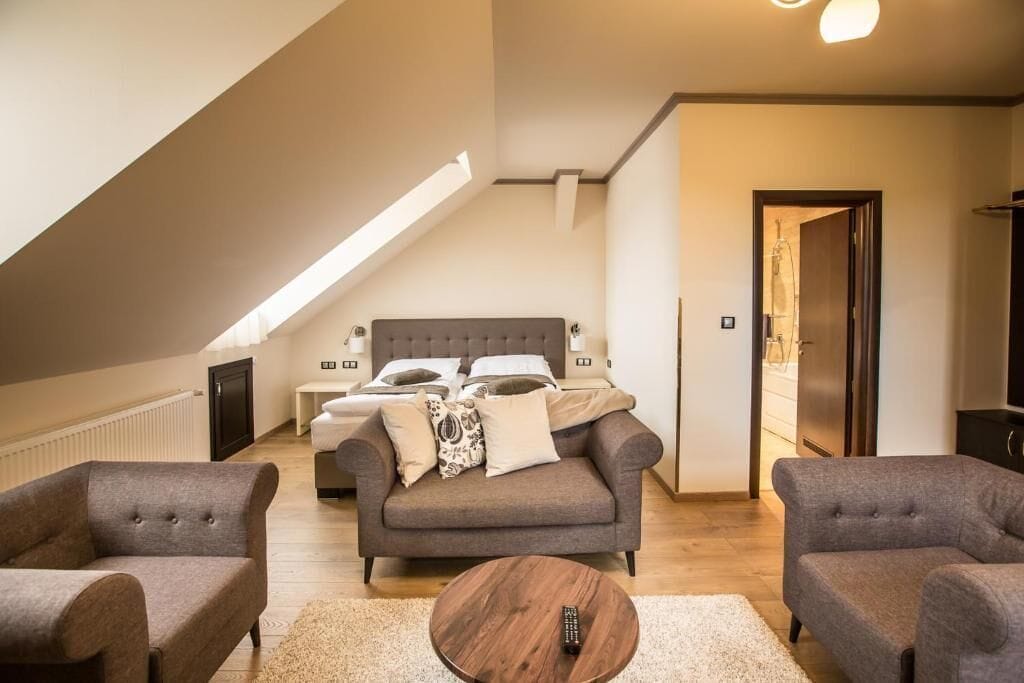 A modern living room with a sofa, two armchairs, a coffee table, and a bed with a headboard.