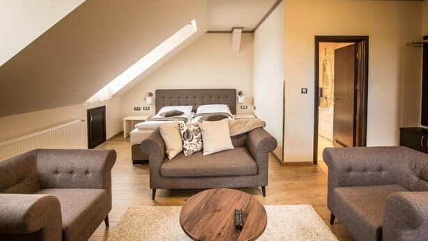 A modern living room with a sofa, two armchairs, a coffee table, and a bed with a headboard.