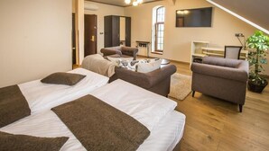 A bedroom with two beds, a sofa, a TV, and a plant.