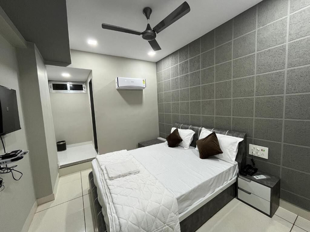 A modern hotel room with a bed, a nightstand, a ceiling fan, and a wall-mounted air conditioner.