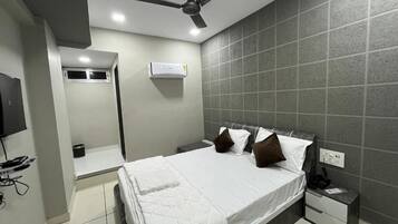 A modern hotel room with a bed, a nightstand, a ceiling fan, and a wall-mounted air conditioner.