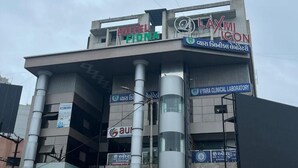 A multi-story building with signs for Hotel Fiona, Laxmi Icon, and Vyara Clinical Laboratory.