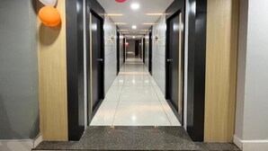 A hallway with a polished floor, doors on both sides, and a ceiling with hanging spherical decorations.