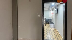 A hallway with a glass door leading to a room with a checkered floor.
