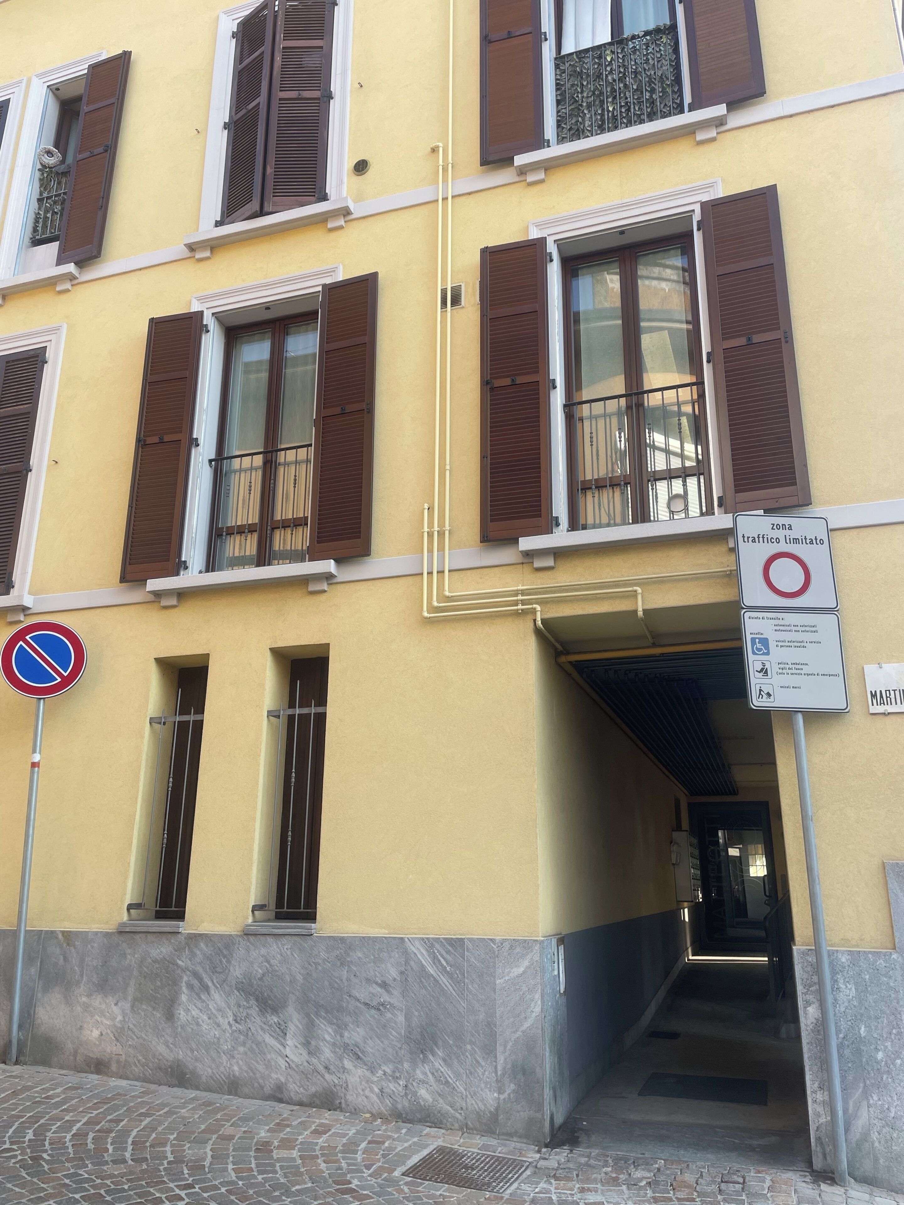 Un edificio con varias ventanas, un cartel de no estacionamiento y una señal de zona de tráfico limitado.