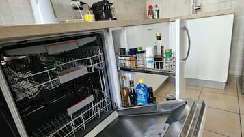 Eine Küche mit einem Geschirrspüler von Bosch, einem Kühlschrank und einer Spüle.