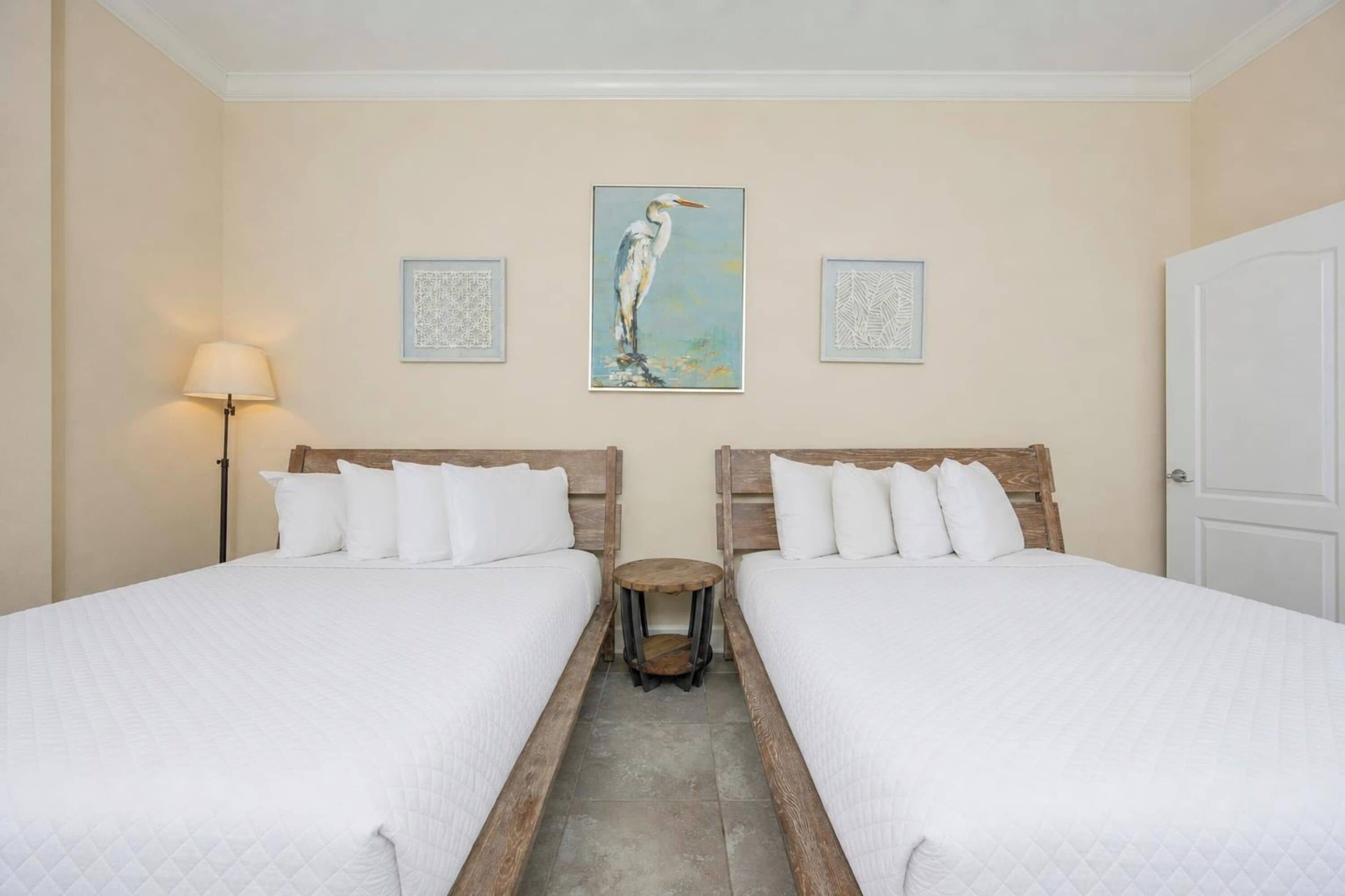 Habitación de hotel con dos camas, una mesita redonda y un cuadro en la pared.