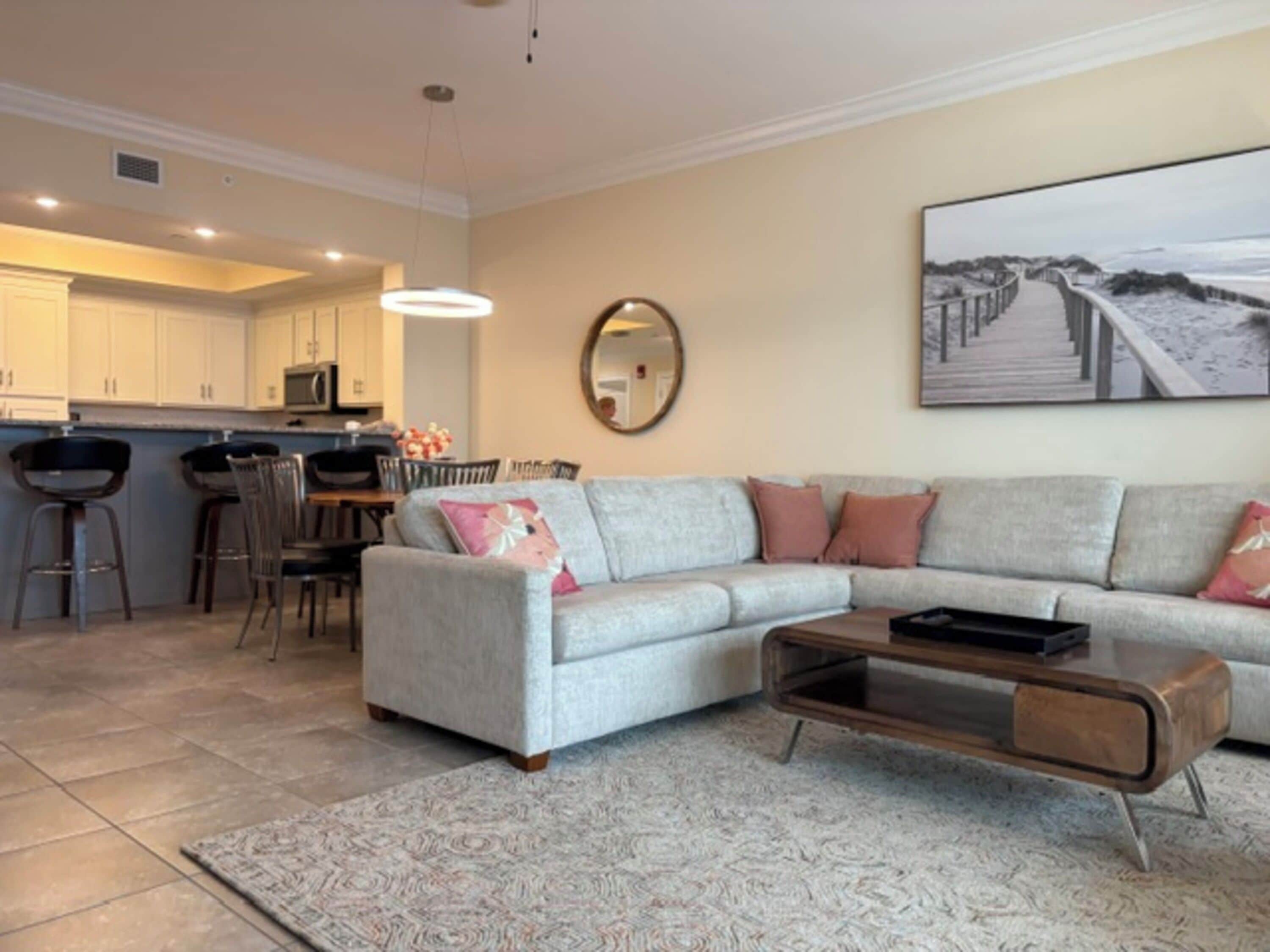 A modern living room with a sectional sofa, a coffee table, and a dining area with chairs and a table.