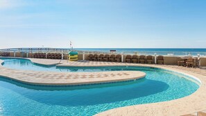 A pool with a curved design, surrounded by lounge chairs and a view of the sea. - Phoenix Orange Beach 1202 (Orange Beach)