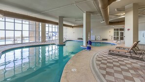 An indoor swimming pool with clear water, surrounded by lounge chairs and a checkered floor. - Phoenix Orange Beach 1202 (Orange Beach)