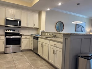 A kitchen with white cabinets, stainless steel appliances, a granite countertop, and a dishwasher. - Phoenix Orange Beach 1202 (Orange Beach)