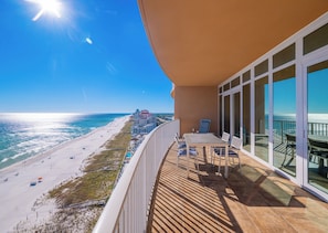 A balcony with a view of the beach and ocean, a table with chairs, and a railing. - Phoenix Orange Beach 1202 (Orange Beach)
