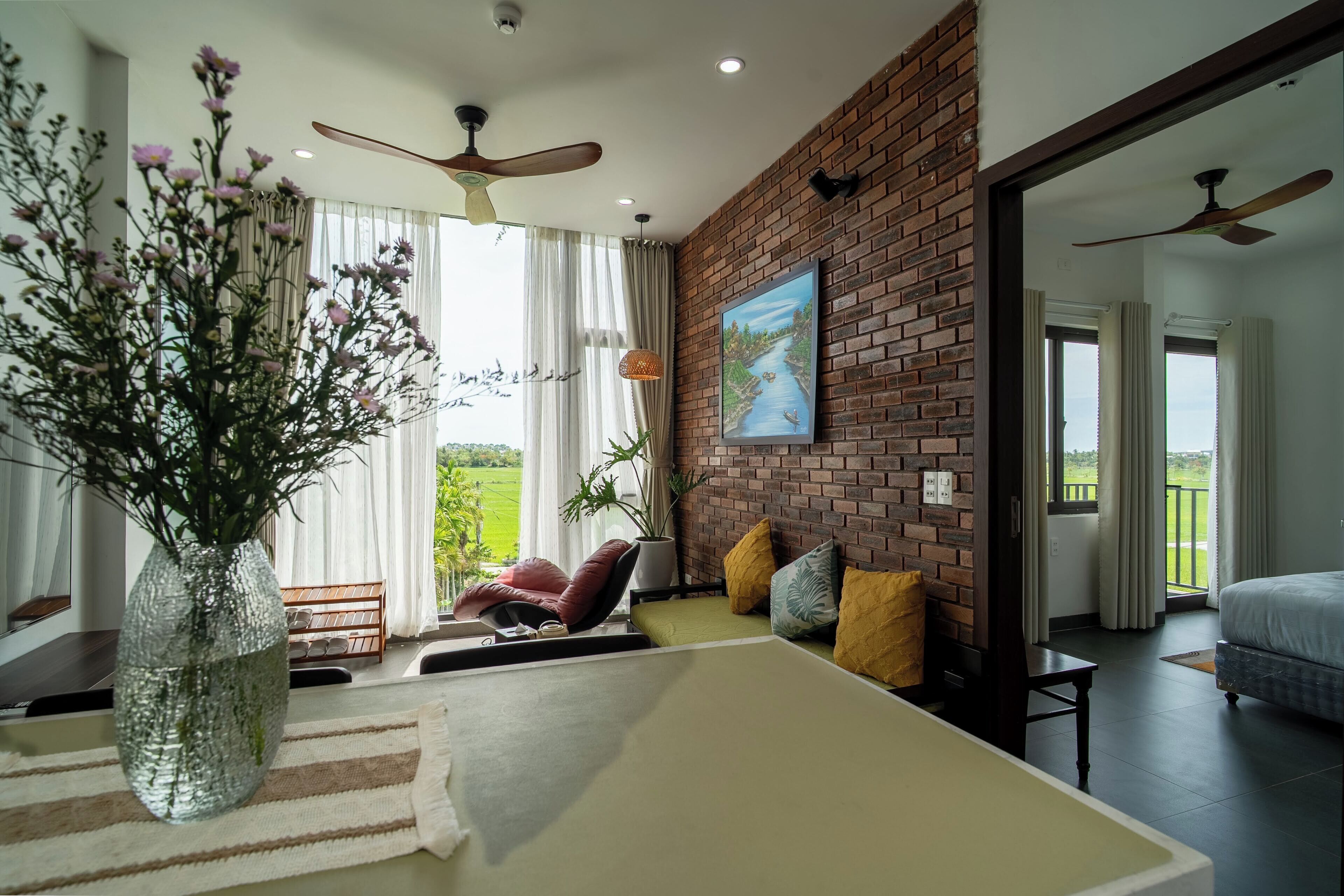 A modern living room with a brick wall, a large window, a sofa, a coffee table, and a ceiling fan.