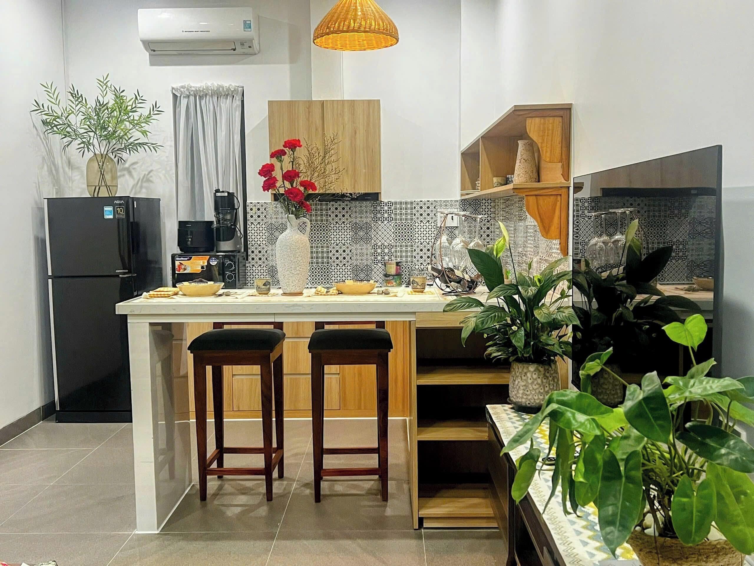 Uma cozinha moderna com ilha central, banquetas, geladeira e diversos eletrodomésticos.