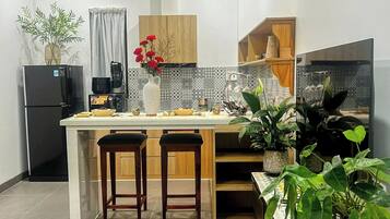 Uma cozinha moderna com ilha central, banquetas, geladeira e diversos eletrodomésticos.
