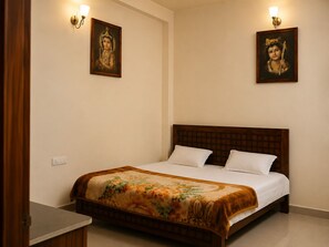 A bedroom with a wooden bed, two wall-mounted light fixtures, and two framed pictures on the wall. - Smiriti Bhawan (Varanasi)