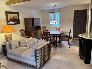 A living room with a sofa, a dining table with chairs, a TV, and a lamp. - Beautiful 1-bedroom cottage in charming Evergreen perfect for relaxing getaway (Evergreen)