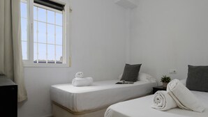 Ein Hotelzimmer mit zwei Betten, einem Fenster mit Blick und einem kleinen Nachttisch mit Pflanze.