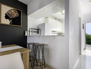 A modern kitchen with white cabinets, a built-in oven, and a large mirror reflecting the space. - Sunstay Flat Torrequebrada (Benalmádena)