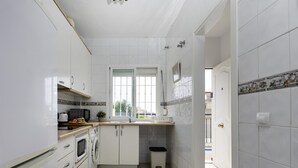Eine schmale Küche mit weißen Schränken, einer Mikrowelle, einem Backofen und einem Spülbecken.