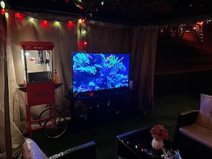A room with a television displaying an underwater scene, a popcorn machine, and a bicycle. - The Manor Cottage (El Cajon)