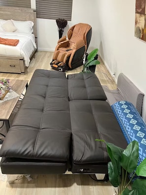 A room with a bed, a massage chair, a sofa, and a coffee table. - The Manor Cottage (El Cajon)