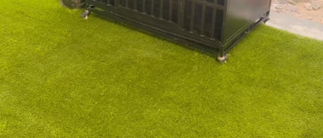 A black metal structure on artificial grass, possibly a piece of outdoor furniture or equipment.