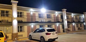 Ein mehrstöckiges Hotel mit einem weißen Auto im Vordergrund.