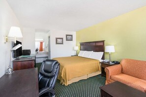 Ein Hotelzimmer mit einem Bett, einem Schreibtisch, einem Sessel, einer Couch und einem Fernseher.