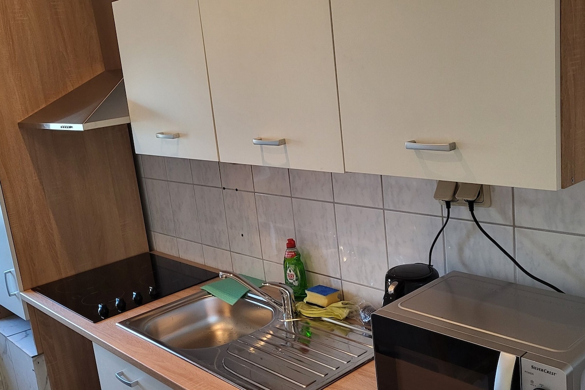 A kitchen with a stainless steel sink, a stove, and cabinets.