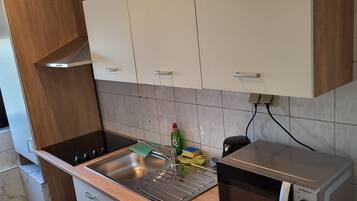 Una cocina con un lavamanos de acero inoxidable, estufa y armarios.