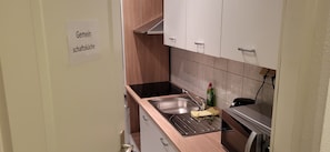 A kitchen with a stainless steel sink, a dish rack, and a bottle of dish soap. - Steakhaus Galgenbach  (Werne)