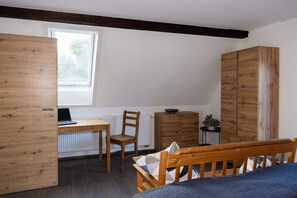A bedroom with a wooden bed, a desk with a laptop, a chair, a wardrobe, and a radiator. - Wohlfühldomizil im Grünen (Leipheim)