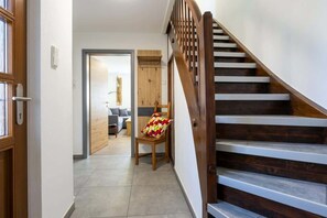 A staircase with wooden steps and a handrail, leading to an interior space with a chair and a sofa. - Wohlfühldomizil im Grünen (Leipheim)