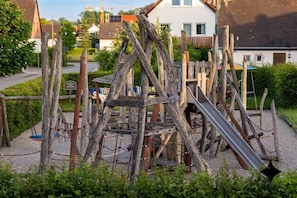 A playground with a slide and climbing structures made of wood and metal. - Wohlfühldomizil im Grünen (Leipheim)