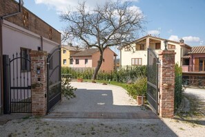 A gated entrance to a residential area with a gravel path leading to a building with a tiled roof. - Private Tuscan Villa with Pool & Spa (Croce)