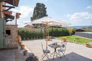 An outdoor patio with a table and chairs, a stone oven, and potted plants. - Private Tuscan Villa with Pool & Spa (Croce)