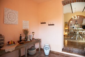 A dining area with a table set for four, a vase, and a wall-mounted light fixture. - Private Tuscan Villa with Pool & Spa (Croce)