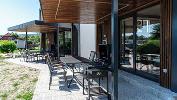 An outdoor patio area with a dining table, chairs, and a grill.