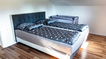 A bedroom with a bed, a chest of drawers, and a wooden floor.