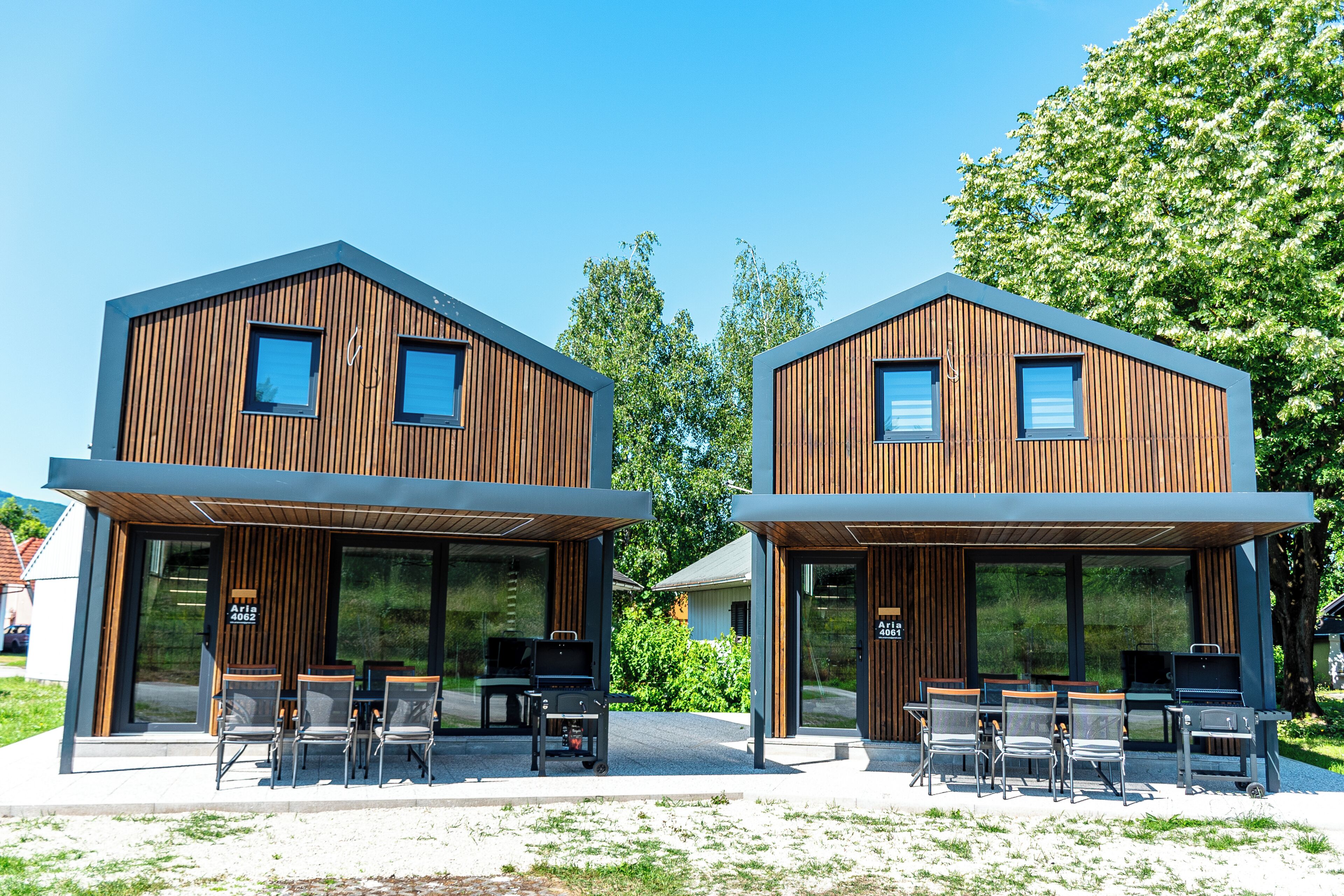 Two modern wooden buildings with large windows and outdoor seating areas.