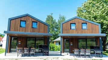 Two modern wooden buildings with large windows and outdoor seating areas.