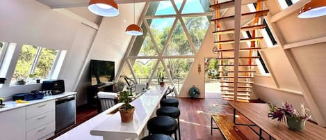 Cocina moderna con una isla central, taburetes de bar y un banco de madera.