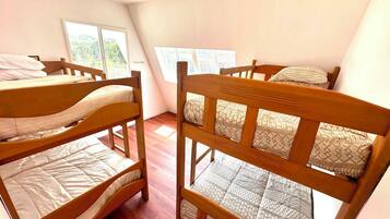 Una habitació amb dos llits superposats de fusta, una finestra que dona a zones verdes i una paret blanca.