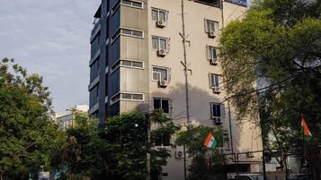 Un edificio de varios pisos con fachada plana, múltiples ventanas y una bandera.