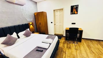 Una habitación de hotel con una cama, un escritorio, un armario y una puerta.