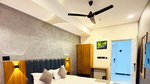 Habitació d'hotel moderna amb un llit gran, amb un panell de fusta al capçal i un ventilador de sostre.