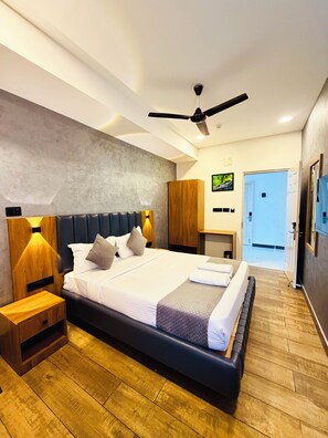 Een moderne hotelkamer met een groot bed, een houten hoofdeinde en een plafondventilator.